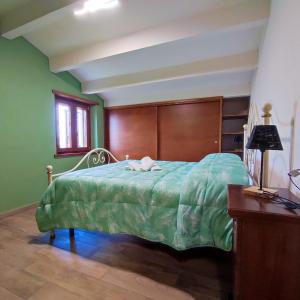 um quarto verde com uma cama com uma cabeceira em madeira em 2 bedrooms house with shared pool garden and wifi at Caprese Michelangelo em Arezzo