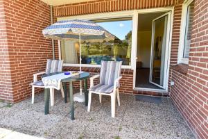 two chairs and a table with an umbrella on a patio at Haus "Luv und Lee" Appartement LEE06 in Döse