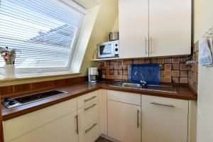 eine Küche mit weißen Schränken und einer Spüle und einem Fenster in der Unterkunft Haus "Luv und Lee" Appartement LEE17 in Döse + 9 Fotos