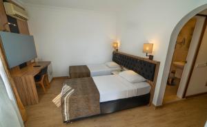 a bedroom with a bed and a desk and a television at Kleopatra Celine Hotel in Alanya
