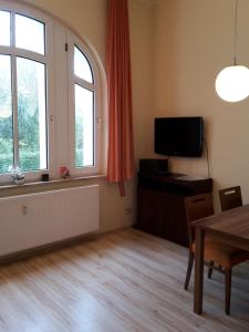 ein Wohnzimmer mit einem Tisch, einem TV und einem Fenster in der Unterkunft Ferienwohnung Villa im Park in Wangerooge