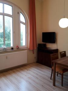 a living room with a table and a tv and window at Ferienwohnung Villa im Park in Wangerooge