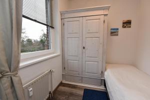 a bedroom with a white cabinet and a window at Haus "Najade" Appartement NAJA8 in Döse