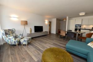 a living room with a couch and chairs and a tv at Haus "Panorama" Appartement PAN022 in Duhnen