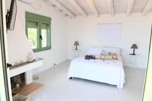 a white bedroom with a bed and a fireplace at Sun Senses - villa with private beach in Ayía Marína
