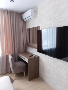 a hotel room with a desk and a television on a wall at Chusovskaya Hotel in Zavod Chusovskoye