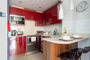uma cozinha com armários vermelhos e um relógio na parede em Swallows em Bournemouth