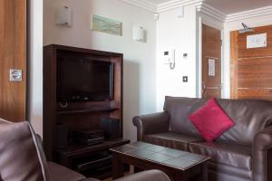 uma sala de estar com um sofá e uma televisão em Swallows em Bournemouth