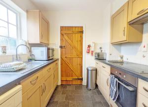 eine Küche mit einem Waschbecken und einer Holztür in der Unterkunft Vane Cottage - Lewes in Lewes