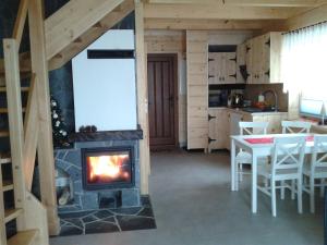 a living room with a fireplace and a table with chairs at DOMEK NA WIERCHU in Kluszkowce