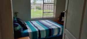 Un dormitorio con una cama con edredón de rayas y una ventana. en Dollery House, en Port Alfred