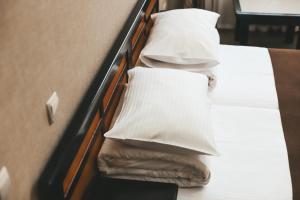 Una cama con sábanas blancas y almohadas. en Georg Palace Hotel en Chernivtsi