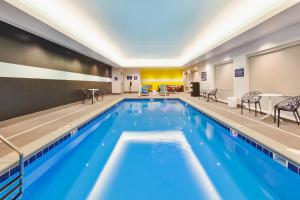 a large swimming pool with blue water in a hotel room at Tru By Hilton Comstock Park Grand Rapids, MI in Comstock Park