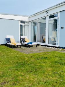 a patio with two chairs and windows on a house at Delightful chalet, overlooking estuary! in Ferryside