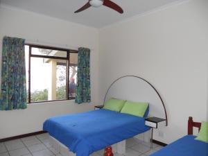 een slaapkamer met een bed met blauwe lakens en een raam bij Shore Breakers in Shelly Beach