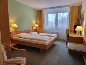 1 dormitorio con cama, escritorio y ventana en Werrapark Resort Hotel Frankenblick en Masserberg