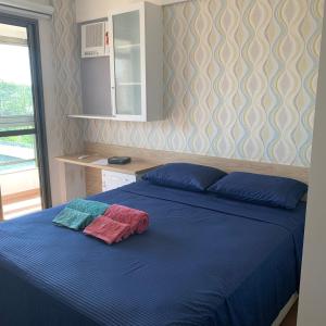 ein Schlafzimmer mit einem blauen Bett mit zwei Handtüchern darauf in der Unterkunft Aconchegante apt com vista para o mar de Camburi in Vitória