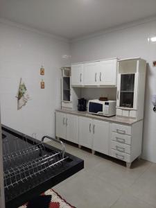 cocina con armarios blancos y microondas en Ótimo apartamento sobreloja com wifi e estacionamento incluso, en Maringá