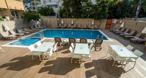 a pool with white tables and chairs next to a building at Kleopatra Celine Hotel in Alanya