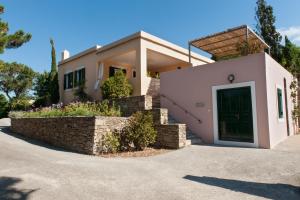 a house with a green door and a stone wall at Montofoli Wine Estate in Karistos