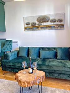 a living room with a green couch and two wine glasses at Apartman Istra- Titova vila in Zlatibor