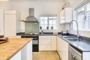 a kitchen with white cabinets and a sink and a stove at Backup-Powered Victorian House at GreenPoint Park in Cape Town