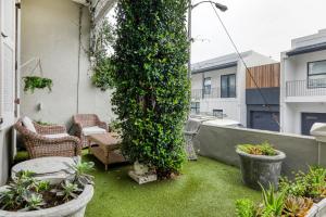 a small patio with grass and plants on a balcony at Backup-Powered Victorian House at GreenPoint Park in Cape Town