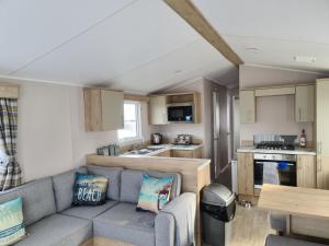 a living room with a couch and a kitchen at Mawgan Pads Perranporth in Cubert