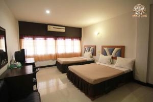 Una habitación de hotel con dos camas y un escritorio. en ไทยโฮเต็ล, en Buriram