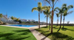 a swimming pool in a yard with palm trees at Alvorada Premium by Sunny Deluxe in Albufeira