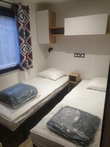 a room with two beds and a window at Mobil home Rainbow, camping les dunes de contis in Saint-Julien-en-Born +24 photos