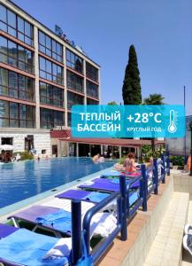 a swimming pool with blue tables and a building at Sochi-Breeze Spa Hotel in Sochi