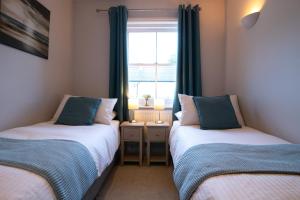 2 camas individuales en una habitación con ventana en Silverdale Mews en Eastbourne