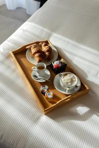 VILLA PORRELLI rooms & spa suite في San Demetrio neʼ Vestini: صينية مع قهوة وكرواسان على سرير