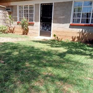 a house with a door and a grass yard at Twende Nanyuki Homes in Nanyuki