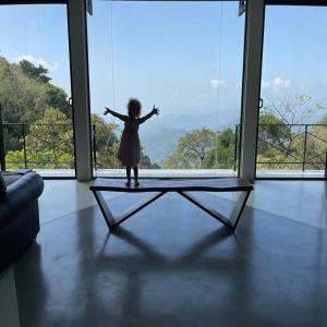 GlenMyu Estate في هابيوتيل: فتاة صغيرة تقف على طاولة أمام النافذة