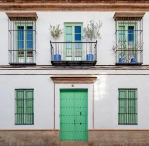 un edificio blanco con una puerta verde y ventanas en Hommyhome Teodosio en Sevilla