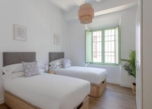 1 dormitorio con 2 camas y ventana en Hommyhome Teodosio, en Sevilla