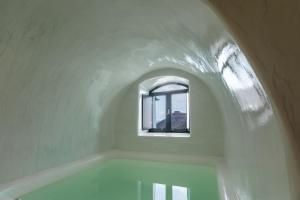 a bath tub in a white room with a window at Doukas Caldera Suites in Fira