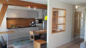 a kitchen with a table and a kitchen with white cabinets at Ferienwohnung am Kniebach in Immenstaad am Bodensee