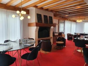 a restaurant with tables and chairs and a fireplace at Hôtel Restaurant La Paix La Robe et le Palais in Forges-les-Eaux