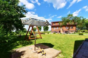 un parque infantil con sombrilla y dos personas de juguete en un columpio en "Trakaitis" Entire Deluxe Villa, en Trakai