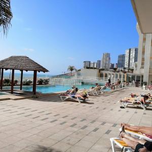 un grupo de personas tumbadas en sillas de jardín junto a una piscina en Departamento en la playa, en Viña del Mar