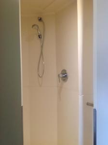a shower with a shower head in a bathroom at ibis budget Orgeval in Orgeval