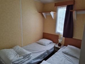 two beds in a small room with a window at Mobil home sur camping 4 étoiles CAP SOLEIL St Denis d'Oléron in La Bétaudière