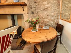 una mesa de madera con un jarrón de flores. en The Old Bakery en Wooler