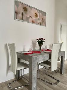 une table à manger avec des chaises blanches et un tableau dans l'établissement Downtown Apartment 4U Leipzig, à Leipzig