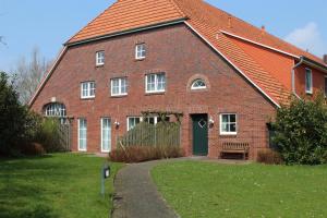 een groot gebouw van rode baksteen met een groene deur bij Ferienhof " Dat grode Gulfhuus" in Tossens