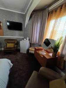 ブラックプールにあるThe Golden Sands B&Bのベッド、デスク、テレビが備わるホテルルームです。