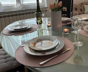 uma mesa de vidro com pratos e copos de vinho em Holiday Home Božica em Ličko Lešće